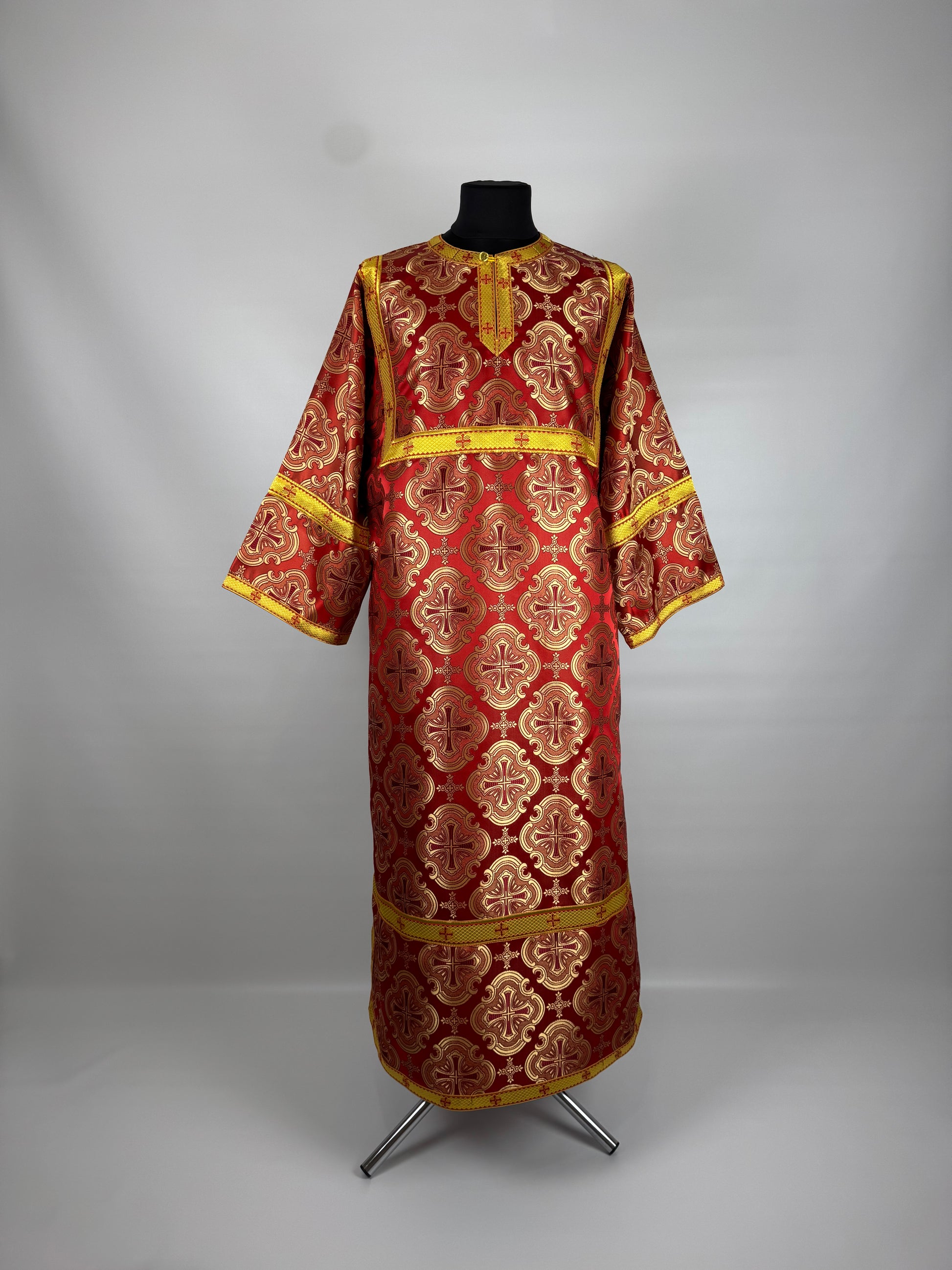 Red and gold embroidered religious robe on a mannequin against a gray background