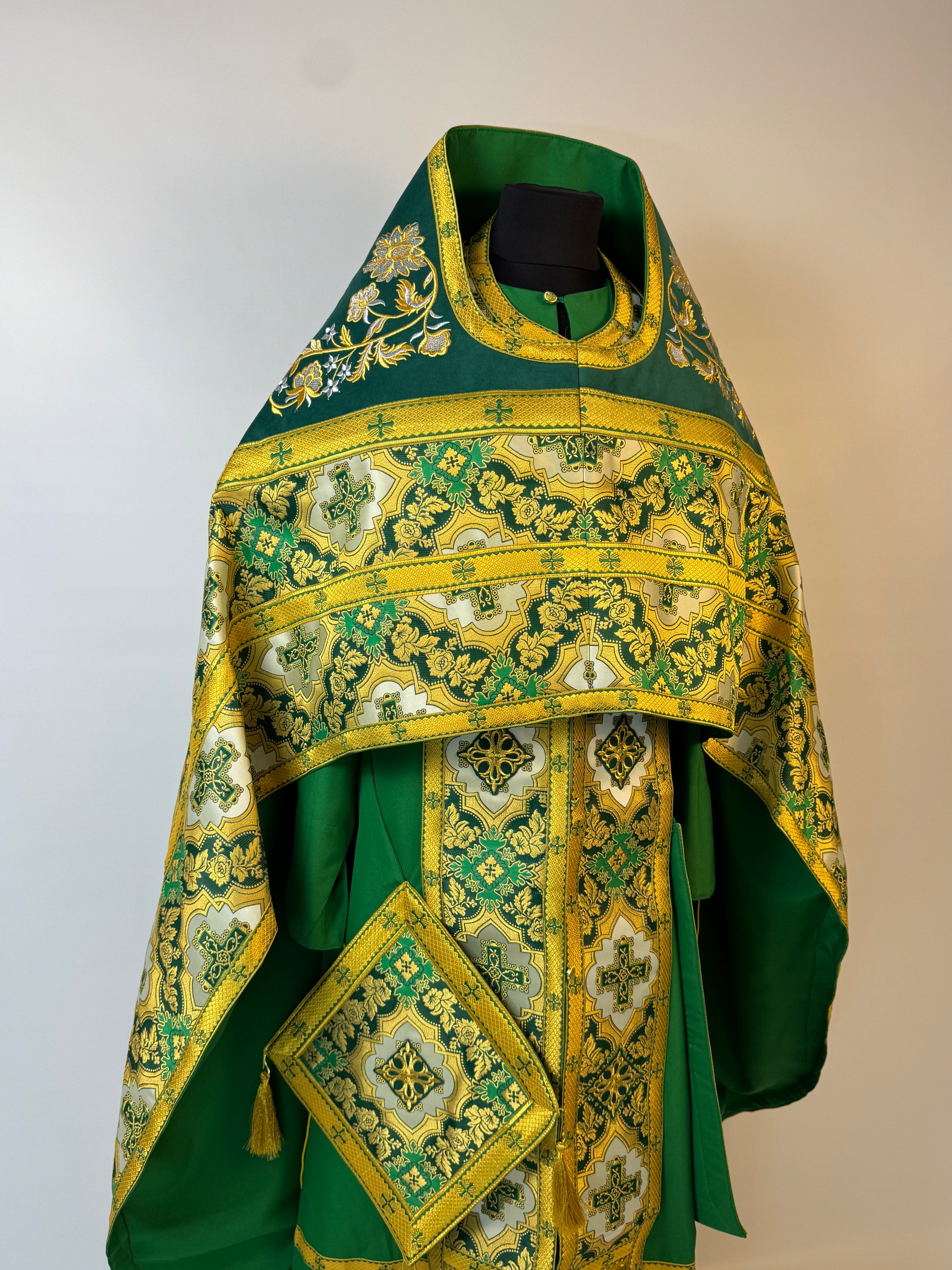 Green and gold embroidered religious vestment on a white background