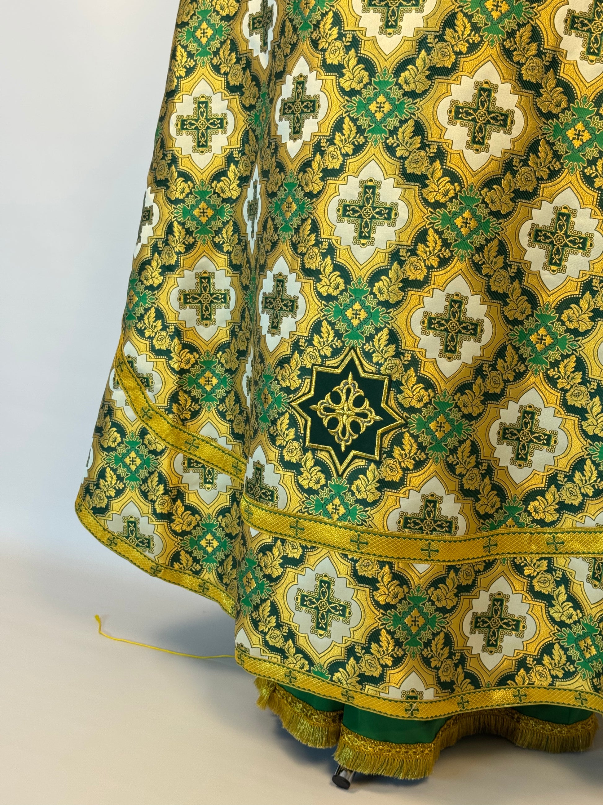 Decorative fabric with intricate gold and green patterns on a white background