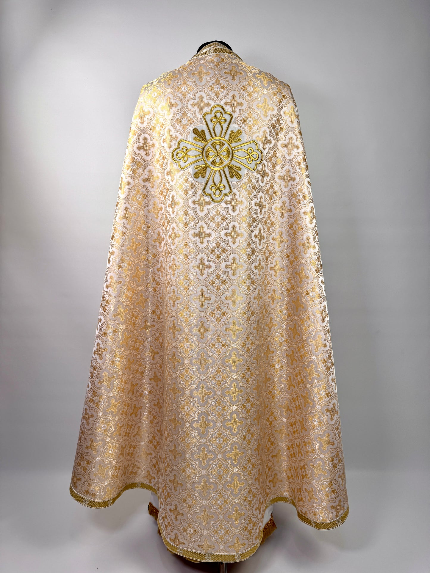 Ecclesiastical vestment with intricate patterns and a cross on a gray background