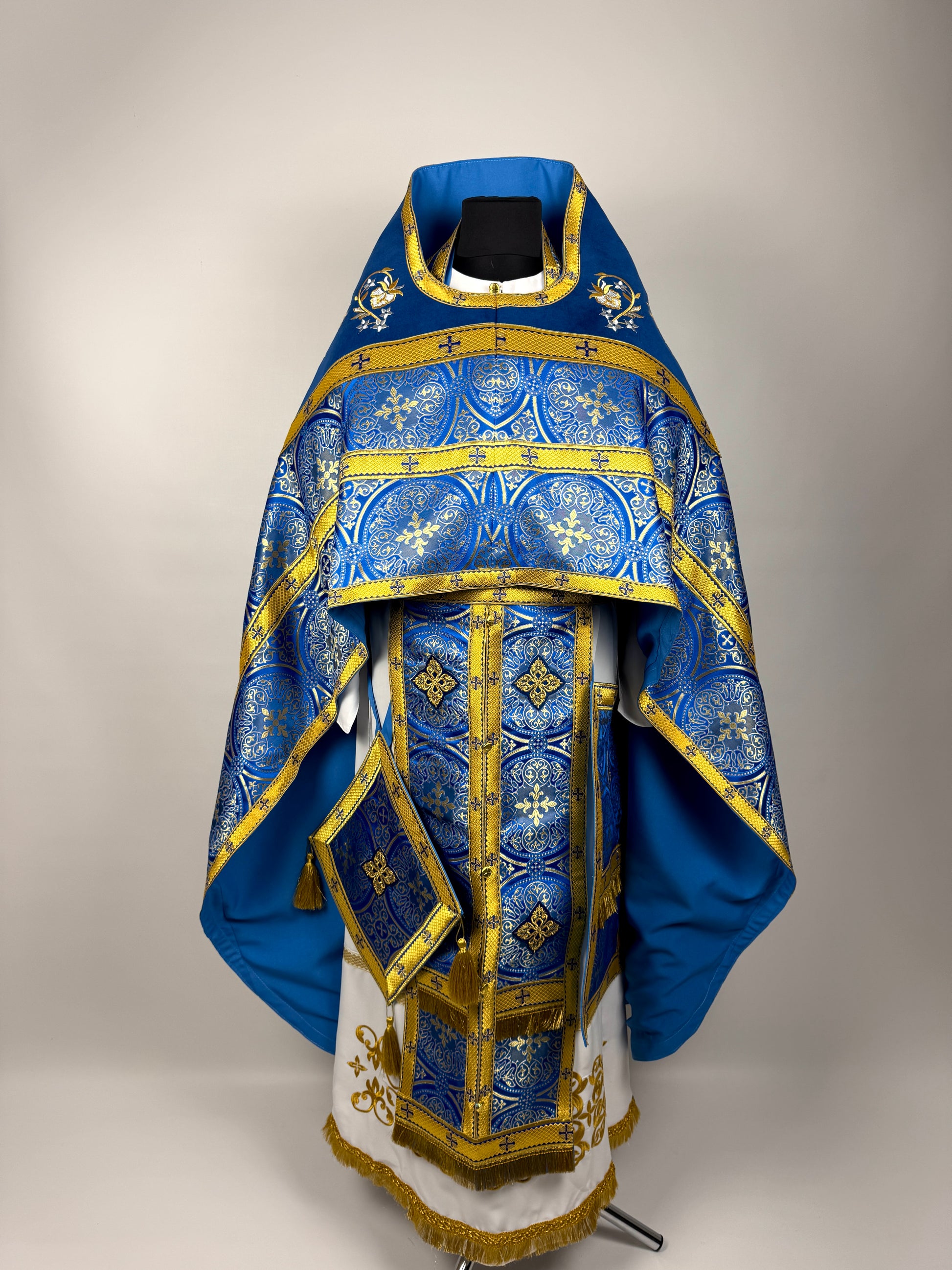 Blue and gold religious vestment on a stand against a gray background