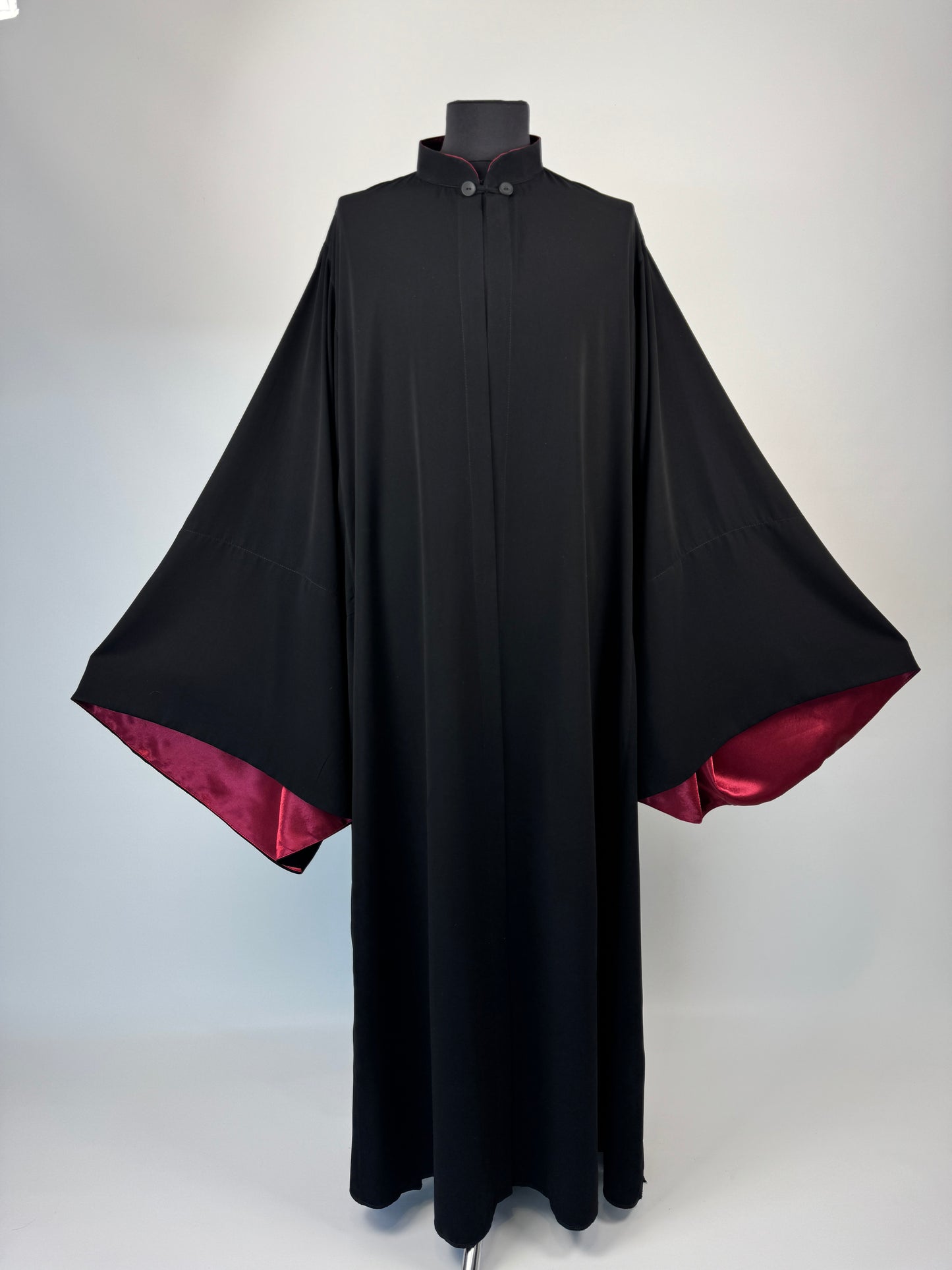 Black outer cassock with burgundy lining on the sleeves