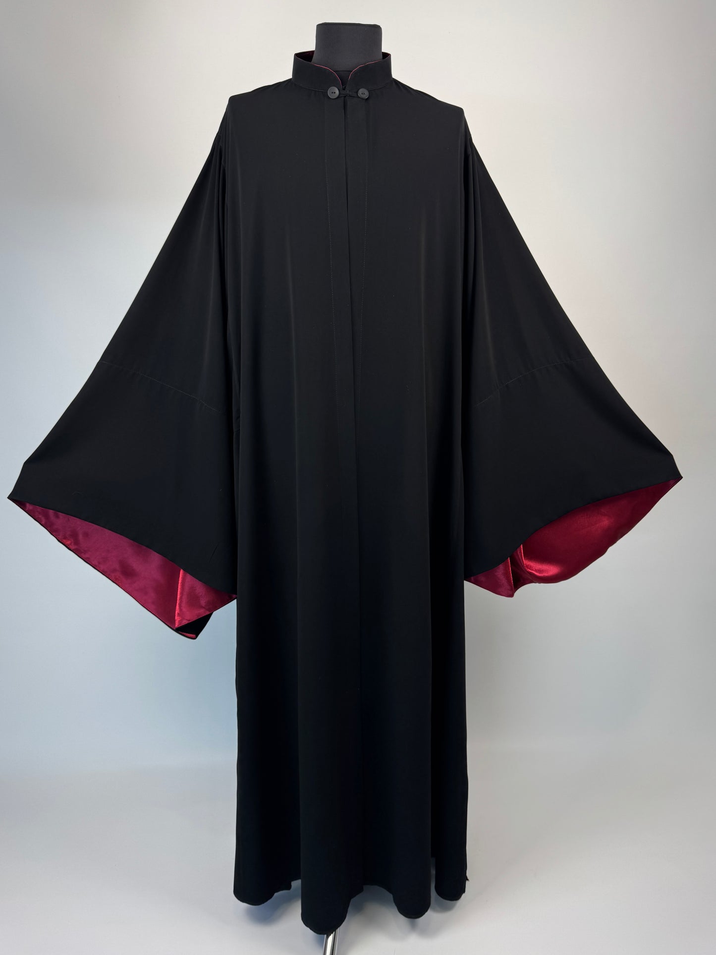 Black outer cassock with burgundy lining on the sleeves