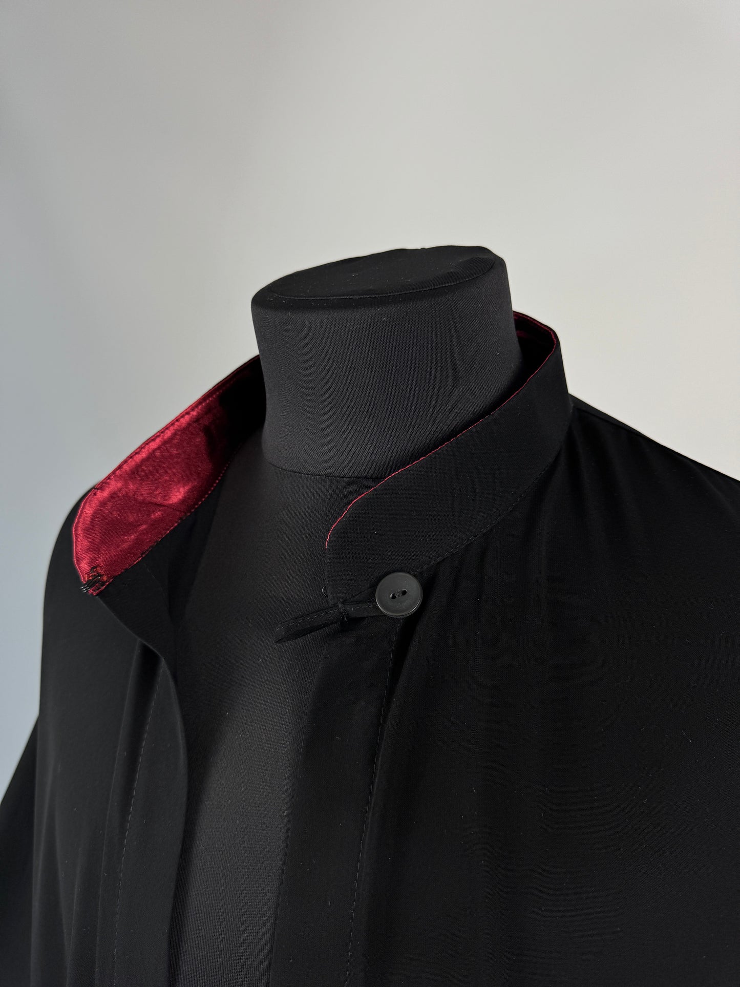 Black outer cassock with burgundy lining on the sleeves