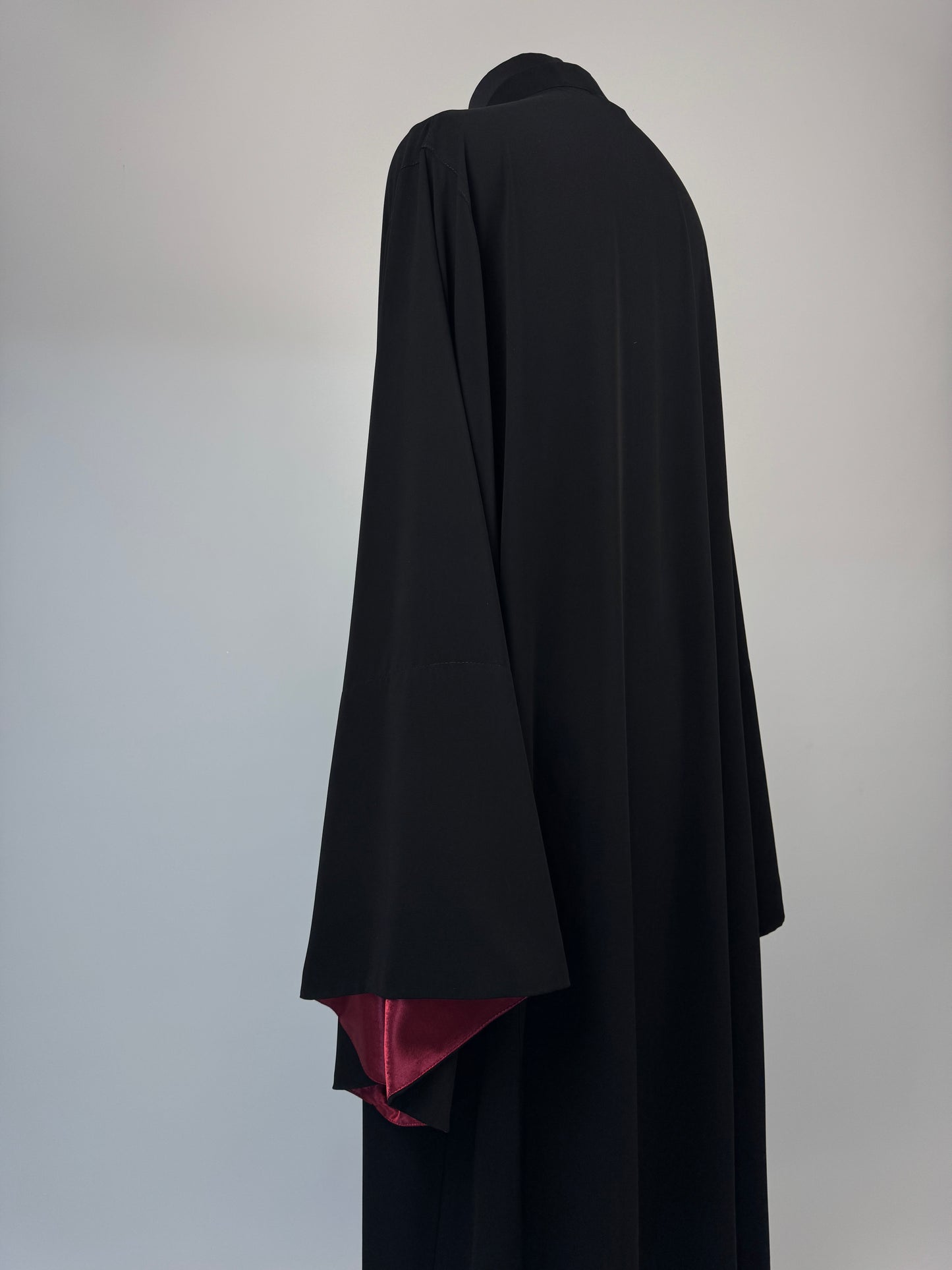 Black outer cassock with burgundy lining on the sleeves
